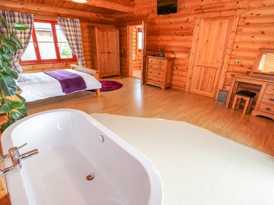 A bedroom with a bathtub wardrobe dresser and dressing table at Beech Lodge in Greetham Rutland