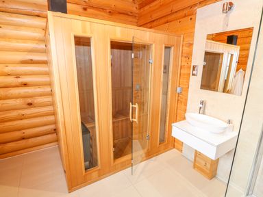 A bathroom with a wooden sauna and a white sink with a mirror at Beech Lodge Greetham Rutland