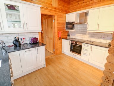 A kitchen with white cabinets black countertops a coffee machine toaster oven and glassware at Beech Lodge in Greetham Rutland