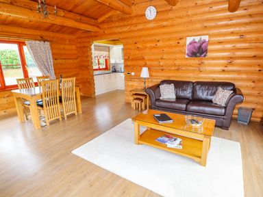 A living room and dining area with wooden furniture and log walls at Beech Lodge in Greetham Rutland