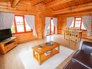 A living room with wooden walls wooden coffee table television and dining table with chairs at Beech Lodge in Greetham Rutland