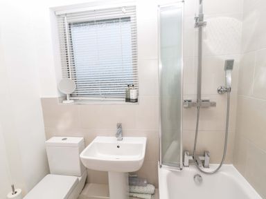 A bathroom with a toilet sink and bathtub with shower at Wynding Apartment in Amble-By-The-Sea