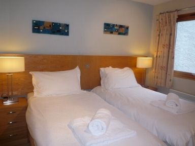 A bedroom with two single beds and bedside lamps at 10 Keswick Bridge in Keswick