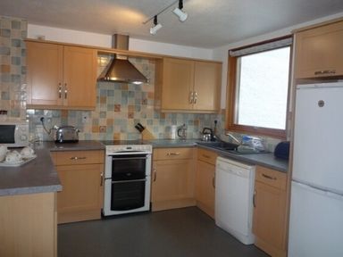 A kitchen with wooden cabinets tiled backsplash stove dishwasher and refrigerator at 16 Keswick Bridge in Keswick