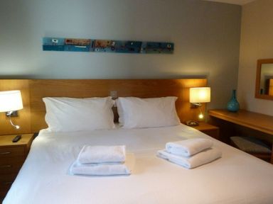A bedroom with a double bed two bedside tables with lamps a desk with a blue vase and a mirror at 16 Keswick Bridge in Keswick