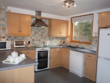 A kitchen with wooden cabinets appliances and a window at 20 Keswick Bridge in Keswick