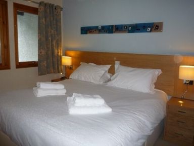 A bedroom with a large bed white bedding two folded towels bedside tables and lamps at 20 Keswick Bridge in Keswick