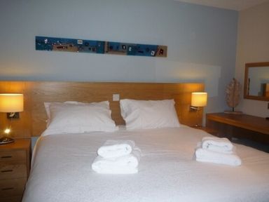 A bedroom with a double bed two bedside lamps folded towels and a mirror at 20 Keswick Bridge in Keswick