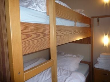 A room with wooden bunk beds and folded towels on a small cabinet at 20 Keswick Bridge in Keswick