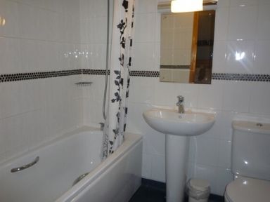 A bathroom with a bathtub shower curtain pedestal sink mirror and toilet at 20 Keswick Bridge in Keswick