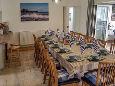 A dining room with a long table set for twelve with bowls plates and striped napkins at Angorfa in Cemaes Bay