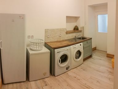 A utility room with a fridge freezer washing machine and sink at Angorfa in Cemaes Bay