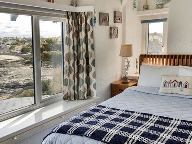 A bedroom with a bed next to a window and a nightstand with a lamp at Angorfa in Cemaes Bay