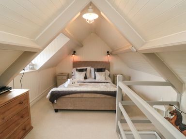 A bedroom with a bed bedside tables a chest of drawers and a wooden horse at Harriets Cottage in Briggswath