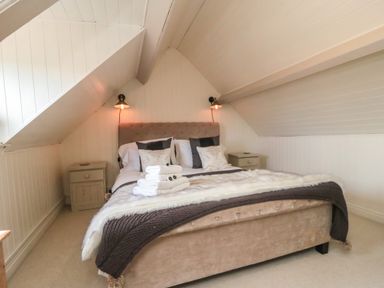 A bedroom with a bed and pillows under a sloped ceiling at Harriets Cottage in Briggswath