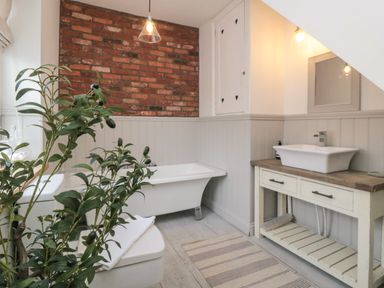 A bathroom with a bathtub toilet sink and a plant at Harriets Cottage in Briggswath