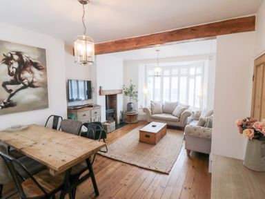 A living room with a dining table, sofa, and television at Harriet's Cottage in Briggswath