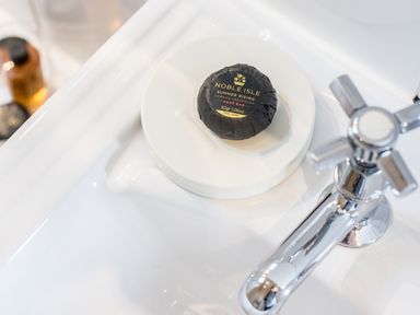A soap bar on a soap dish next to a chrome faucet on a white bathroom sink at Reflection in Longtown