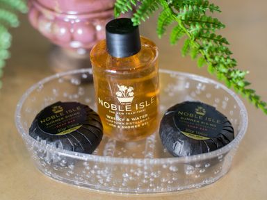 A tray with two soap bars and a bottle of bath and shower gel with green fern leaves at Reflection in Longtown
