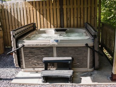 A hot tub with steps on a gravel area at Reflection in Longtown