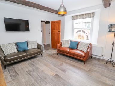 A living room with two sofas and a wall-mounted TV at Llys Alaw in Llangernyw
