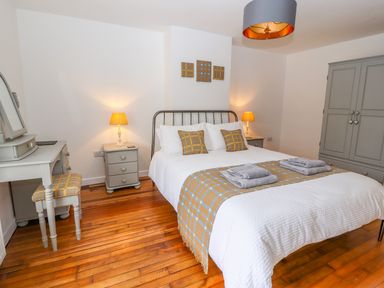 A bedroom with a double bed bedside tables lamps a dressing table with stool and a wardrobe at Llys Alaw in Llangernyw