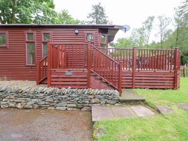 A wooden cabin with a fenced deck and stone wall at 10 Thirlmere White Cross Bay near Troutbeck Bridge