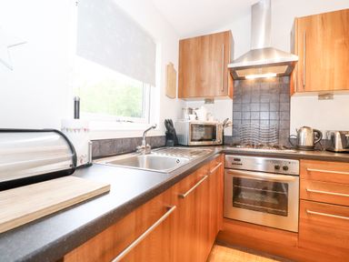 A kitchen with wooden cabinets a stainless steel oven microwave sink and countertop appliances at 10 Thirlmere White Cross Bay near Troutbeck Bridge