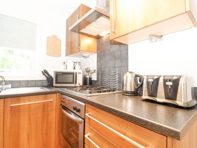A kitchen countertop with a toaster kettle microwave oven and utensils at 10 Thirlmere White Cross Bay near Troutbeck Bridge
