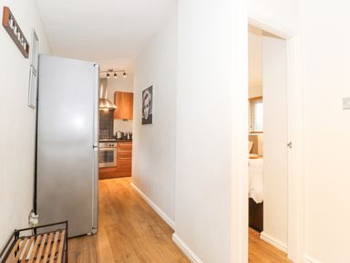 A narrow hallway with wooden floor leading to a kitchen and a partially visible bedroom at 10 Thirlmere White Cross Bay near Troutbeck Bridge