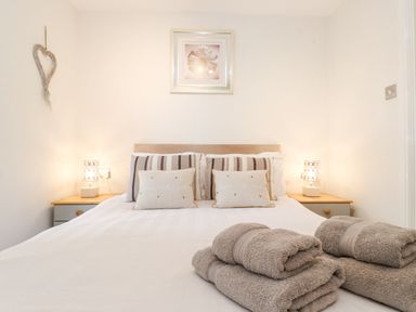 A bedroom with a bed with pillows and folded towels on the bed at 10 Thirlmere White Cross Bay near Troutbeck Bridge