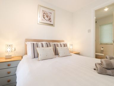 A bedroom with a bed and nightstands with lamps and a bathroom visible through an open door at 10 Thirlmere White Cross Bay near Troutbeck Bridge