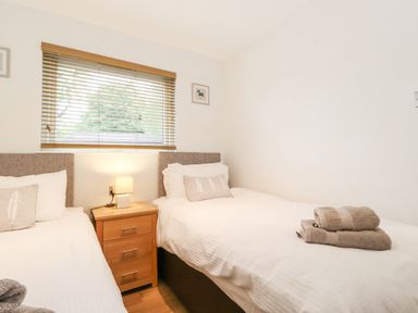 A bedroom with two single beds separated by a wooden bedside table with a lamp at 10 Thirlmere White Cross Bay near Troutbeck Bridge