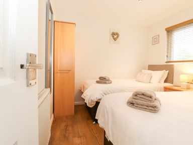 A bedroom with two single beds a wooden wardrobe a bedside table with a lamp and folded towels on the beds at 10 Thirlmere White Cross Bay near Troutbeck Bridge