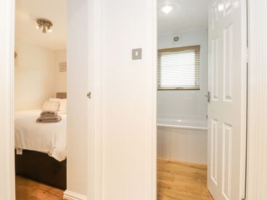 A bedroom with a bed and folded towels and a bathroom with a bathtub and window blinds at 10 Thirlmere White Cross Bay near Troutbeck Bridge
