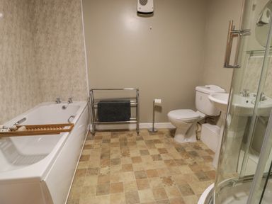 A bathroom with a bathtub a towel rack a toilet a sink and a glass shower enclosure at Ty Uchaf in Dyffryn Ardudwy