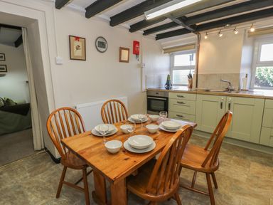 A kitchen with a wooden dining table set with plates bowls and glasses and light green cabinets at Ty Uchaf in Dyffryn Ardudwy