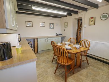 A kitchen with wooden dining table and chairs set with bowls and glasses at Ty Uchaf in Dyffryn Ardudwy
