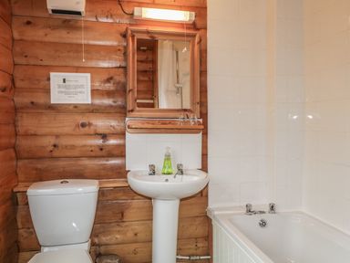 A bathroom with a toilet sink mirror and bathtub at Otter Lodge in Strathpeffer
