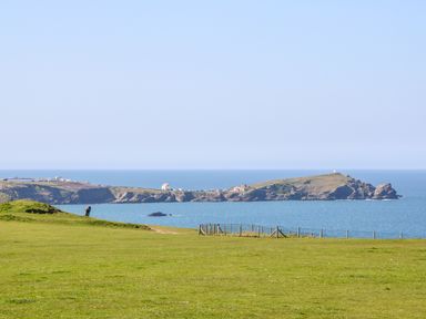 A grassy field with a person and a fence overlooking the sea and a rocky coastline at Ocean Seven in Newquay