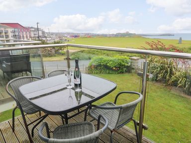 A balcony with a table and chairs overlooking a grassy area at Ocean Seven in Newquay
