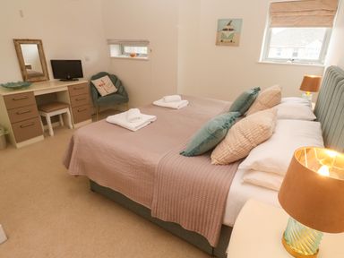 A bedroom with a bed, desk, chair, and lamp at Ocean Seven in Newquay