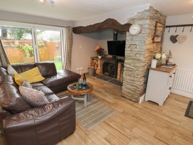 A living room with a brown leather sofa wooden coffee table fireplace and a TV at Bwthyn Y Jacdo in Crymych