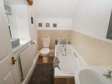 A bathroom with a bathtub toilet sink and a window at Bwthyn Y Jacdo in Crymych