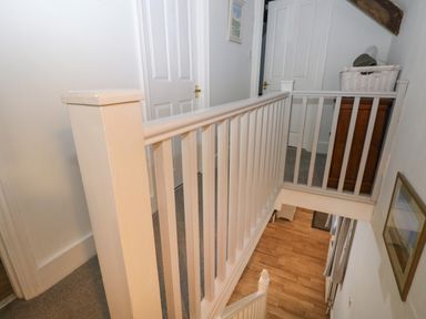 A hallway with white railing overlooking wooden stairs and doors in the background at Bwthyn Y Jacdo in Crymych