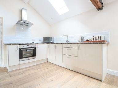 A kitchen with white cabinets a built in oven a microwave a kettle and a toaster at Granary 2 in Madley