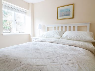 A bedroom with a white bedspread white pillows a bedside table with a lamp and a window at Granary 1 Madley near Hereford
