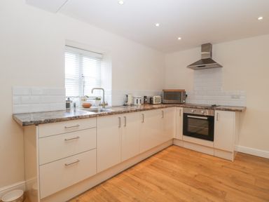 A kitchen with white cabinets a window a sink a toaster kettle and microwave at Granary 1 Madley near Hereford