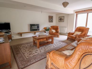 A living room with brown leather sofas a wooden coffee table and a television at The Barn in Abergavenny