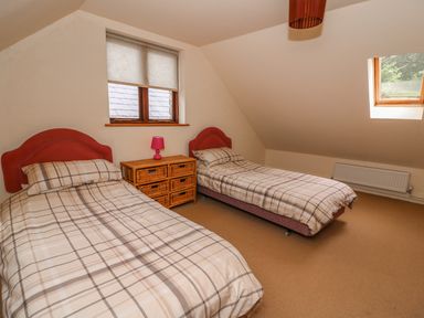 A bedroom with two single beds wooden chest of drawers and a window at The Barn in Abergavenny